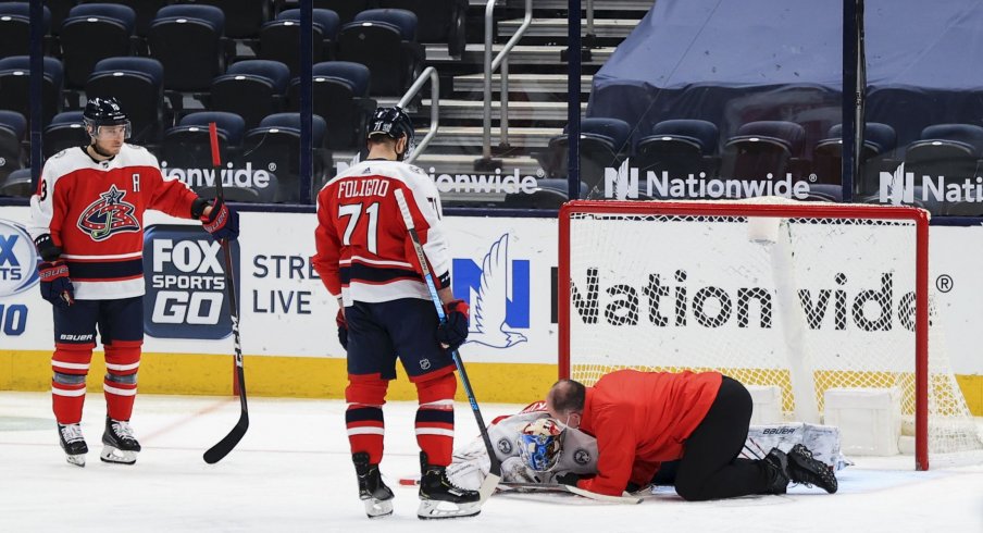 Feb 20, 2021; Columbus, Ohio, USA; Columbus Blue Jackets goaltender Elvis Merzlikins (90) is looked after by Columbus head athletic trainer Mike Vogt (right) during a stop in play against the Nashville Predators in the third period at Nationwide Arena.