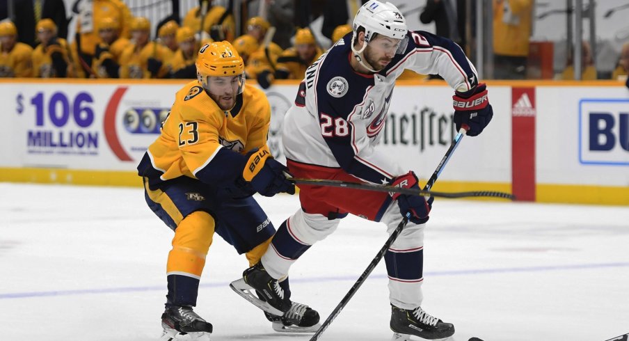 Feb 27, 2021; Nashville, Tennessee, USA; Columbus Blue Jackets right wing Oliver Bjorkstrand (28) takes a shot on goal against Nashville Predators right wing Rocco Grimaldi (23) during the second period at Bridgestone Arena.