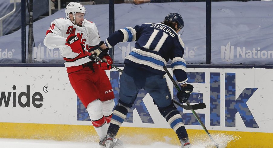 Mar 25, 2021; Columbus, Ohio, USA; Carolina Hurricanes left wing Jordan Martinook (48) and Columbus Blue Jackets center Kevin Stenlund (11) battle for the puck during the third period at Nationwide Arena.