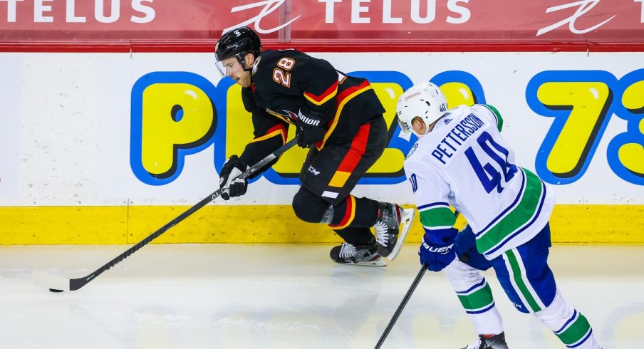 Elias Lindholm protects the puck from Elias Pettersson