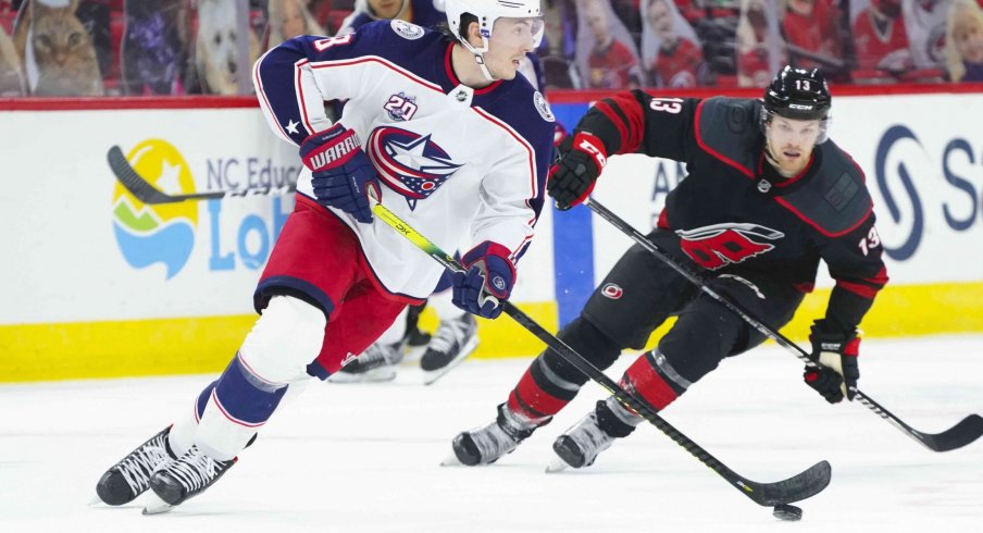 Mar 18, 2021; Raleigh, North Carolina, USA; Columbus Blue Jackets defenseman Zach Werenski (8) skates with the puck past Carolina Hurricanes left wing Warren Foegele (13) at PNC Arena.