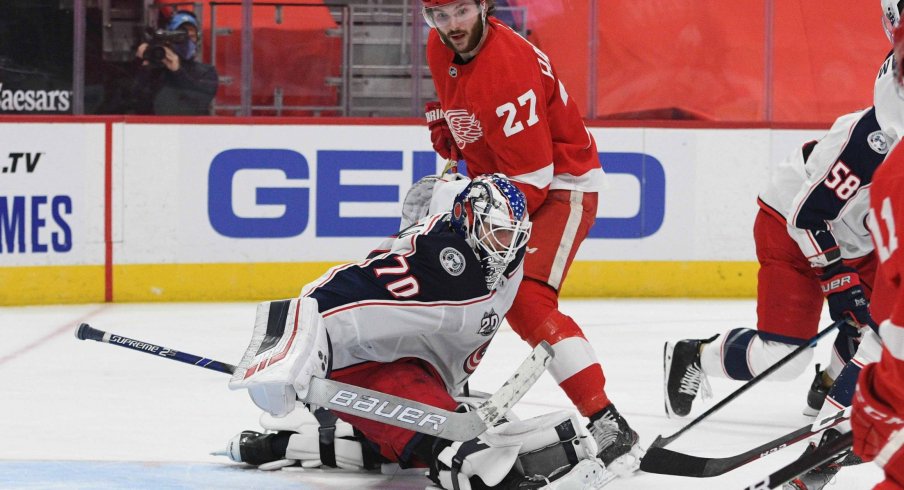 Jan 18, 2021; Detroit, Michigan, USA; Columbus Blue Jackets goaltender Joonas Korpisalo (70) makes a save in front of Detroit Red Wings center Michael Rasmussen (27) during the second period at Little Caesars Arena.