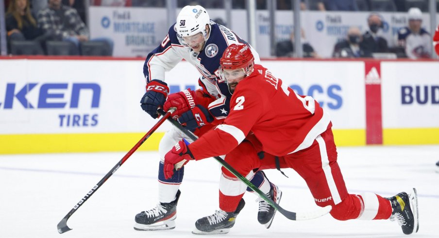 Oct 19, 2021; Detroit, Michigan, USA; Columbus Blue Jackets left wing Eric Robinson (50) and Detroit Red Wings defenseman Nick Leddy (2) battle for the puck in the first period at Little Caesars Arena.