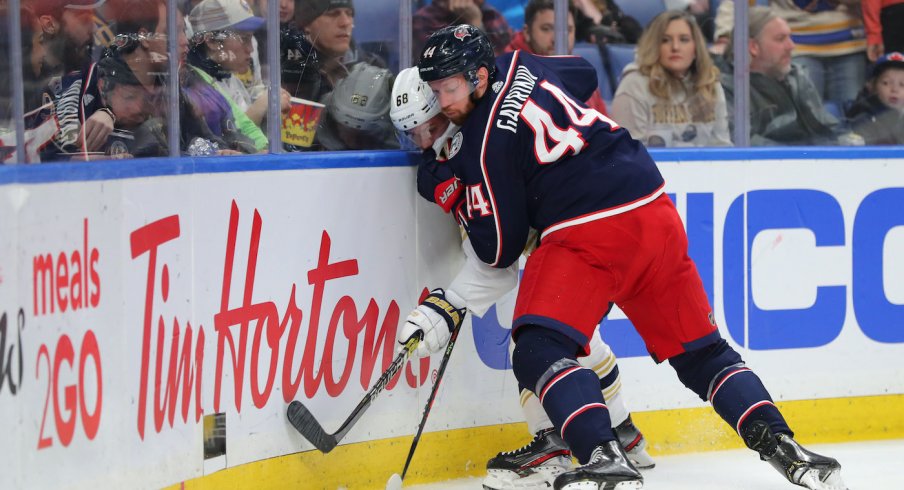 Columbus Blue Jackets defenseman Vladislav Gavrikov (44) pins Buffalo Sabres left wing Victor Olofsson (68) on the boards as he goes for the puck during the second period at KeyBank Center.