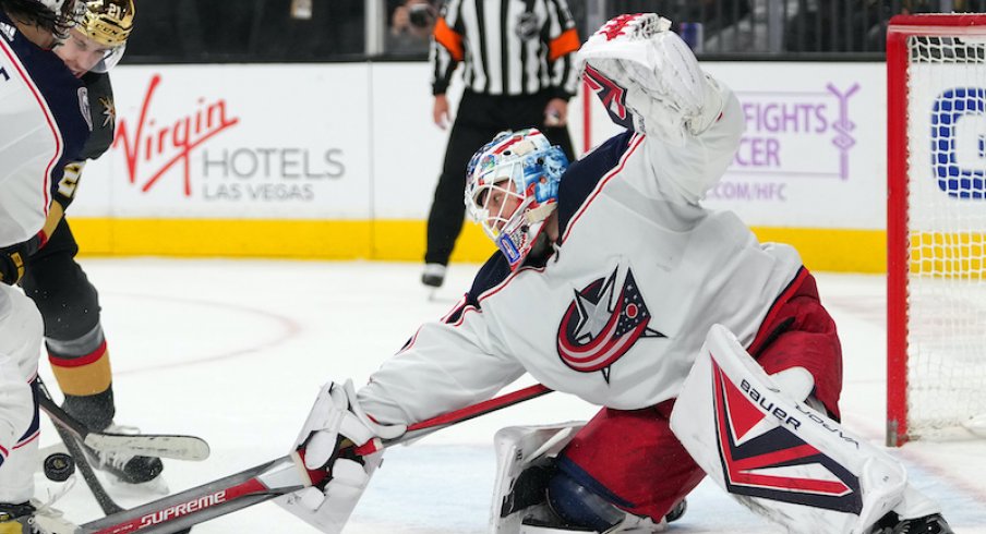 Elvis Merzlikins of the Columbus Blue Jackets reaches for the puck against the Vegas Golden Knights at T-Mobile Arena.