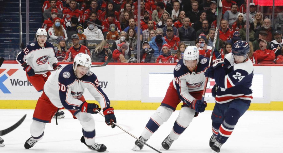 Dec 4, 2021; Washington, District of Columbia, USA; Columbus Blue Jackets left wing Eric Robinson (50) reaches for the puck in front of Washington Capitals center Connor McMichael (24) during the second period at Capital One Arena.
