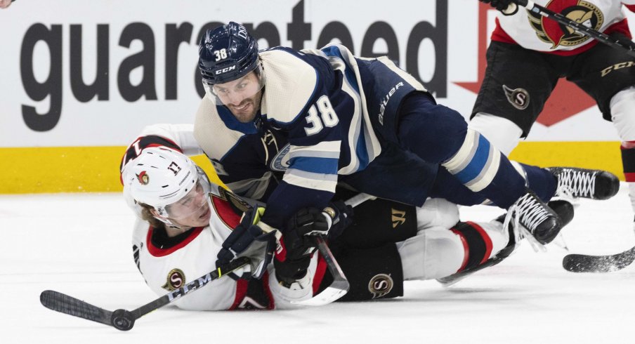 Jan 23, 2022; Columbus, Ohio, USA; Columbus Blue Jackets center Boone Jenner (38) tries to maintain control of the puck as he falls to the ice with Ottawa Senators center Adam Gaudette (17) in the second period at Nationwide Arena.