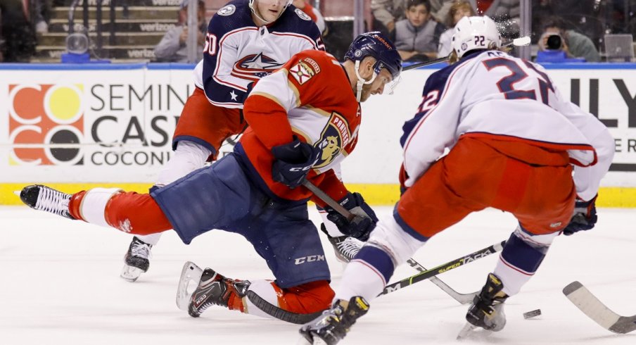 Eric Robinson and Jake Bean try to take the puck from Jonathan Huberdeau 