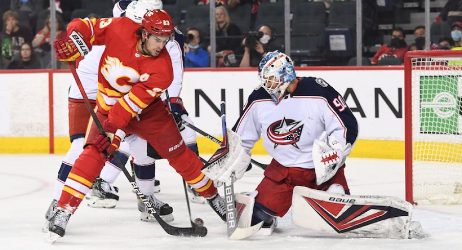 Calgary Flames forward Sean Monahan playing the puck against Columbus Blue Jackets goalie Elvis Merzlikins during the first period in Calgary.