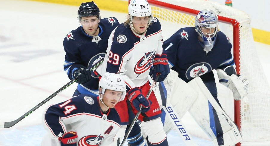 Winnipeg Jets defenseman Neal Pionk jostles for position with Columbus Blue Jackets forward Patrik Laine in front of Winnipeg Jets goalie Eric Comrie during the third period at Canada Life Centre