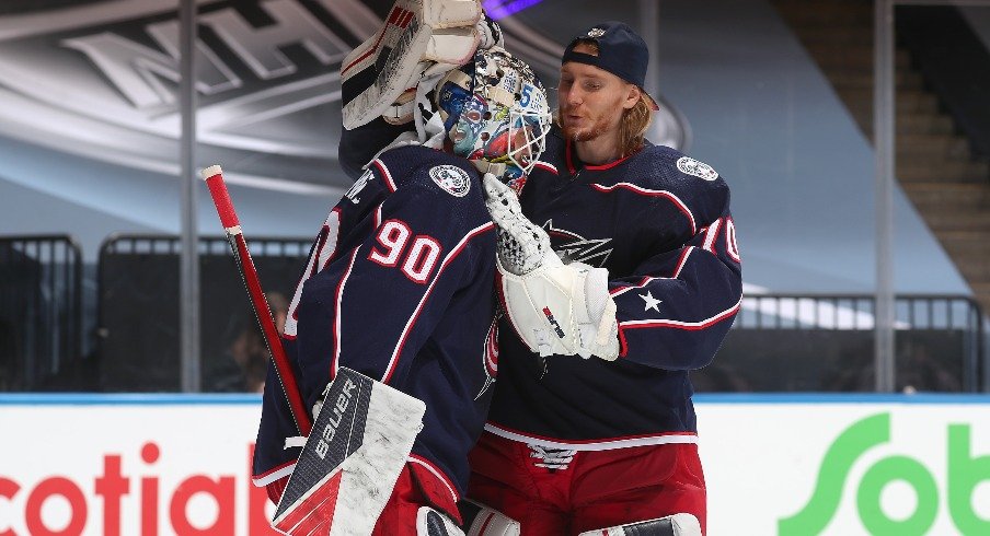 Goaltender Joonas Korpisalo of the Columbus Blue Jackets congratulates fellow netminder Elvis Merzlikins after an exhibition game against the Boston Bruins prior to the 2020 NHL Stanley Cup Playoffs.