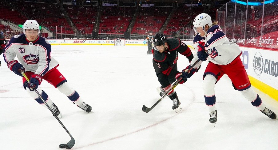 Columbus Blue Jackets defenseman Zach Werenski with right wing Patrik Laine skates with the puck past Carolina Hurricanes defenseman Brett Pesce at PNC Arena.