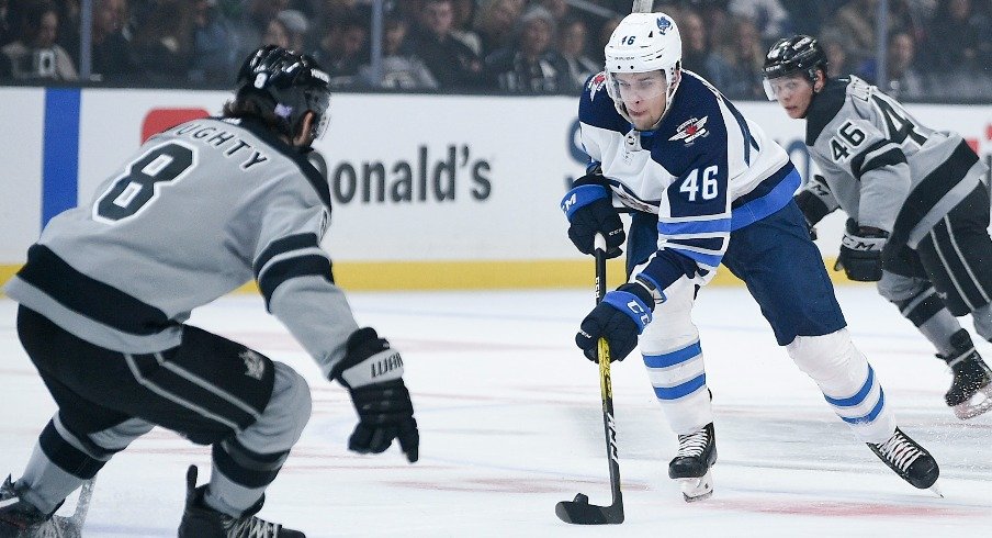 Winnipeg Jets left wing Joona Luoto moves the puck past Los Angeles Kings center Blake Lizotte while defenseman Drew Doughty defends during the first period at Staples Center.