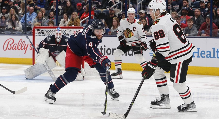 Patrick Kane looks to pass as Vladislav Gavrikov defends 