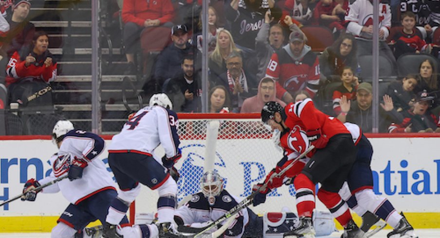 Elvis Merzlikins makes a save on Nathan Bastian in the Blue Jackets vs. Devils game.