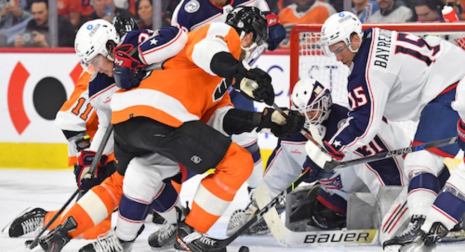 Philadelphia Flyers left wing Noah Cates (49) battles for the puck with Columbus Blue Jackets defenseman Andrew Peeke (2) and defenseman Gavin Bayreuther (15) during the second period at Wells Fargo Center.