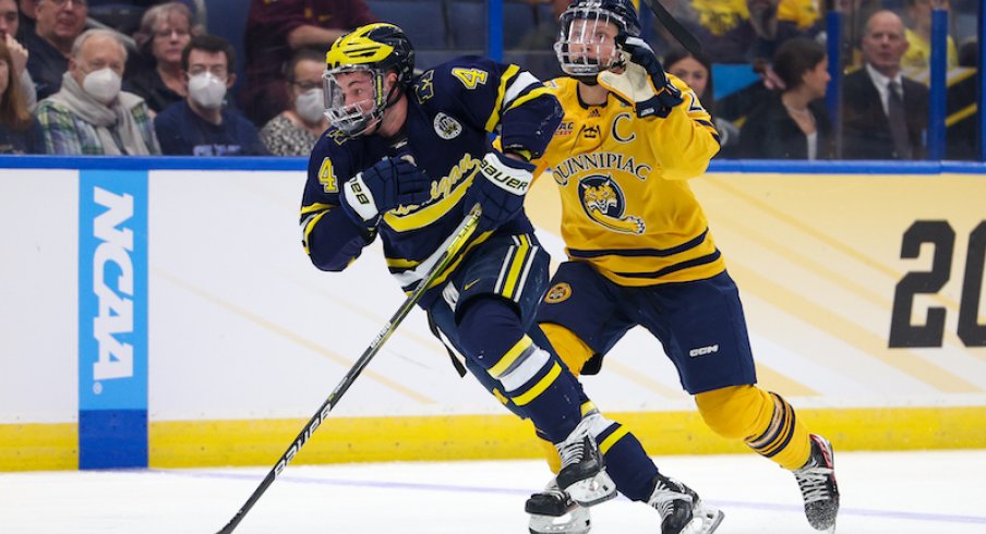 Michigan' Gavin Brindley and Quinnipiac' Zach Metsa battle for the puck during the first period in the semifinals of the 2023 Frozen Four college ice hockey tournament at Amalie Arena.