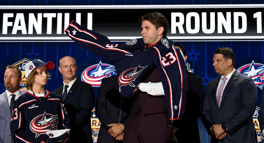 Columbus Blue Jackets draft pick Adam Fantilli puts on his sweater after being selected with the third pick in round one of the 2023 NHL Draft at Bridgestone Arena. 