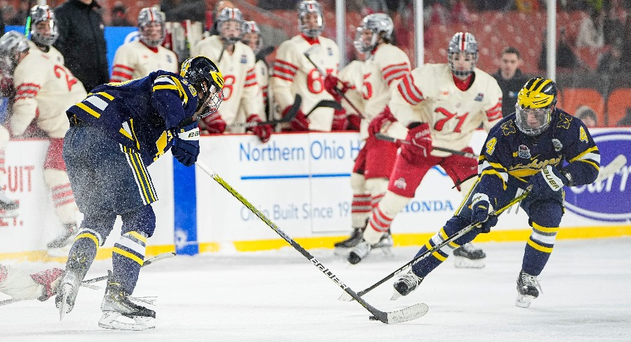 Michigan Wolverines forwards Gavin Brindley (4) and Adam Fantilli (19) reach for a puck during the Faceoff on the Lake outdoor NCAA men's hockey game against the Ohio State Buckeyes at FirstEnergy Stadium.