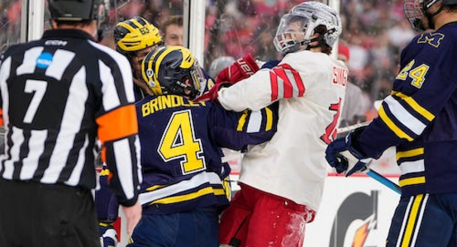 Ohio State Buckeyes forward Tate Singleton (13) hits Michigan Wolverines forward Gavin Brindley (4) during the first period of the Faceoff on the Lake outdoor NCAA men's hockey game at FirstEnergy Stadium.