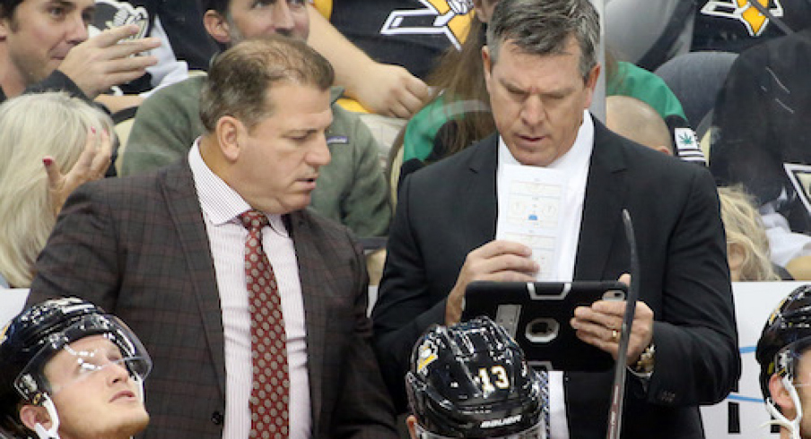 Pittsburgh Penguins assistant coach Mark Recchi (left) and head coach Mike Sullivan (right) look at a replay on a tablet device against the Winnipeg Jets during the second period at PPG PAINTS Arena.