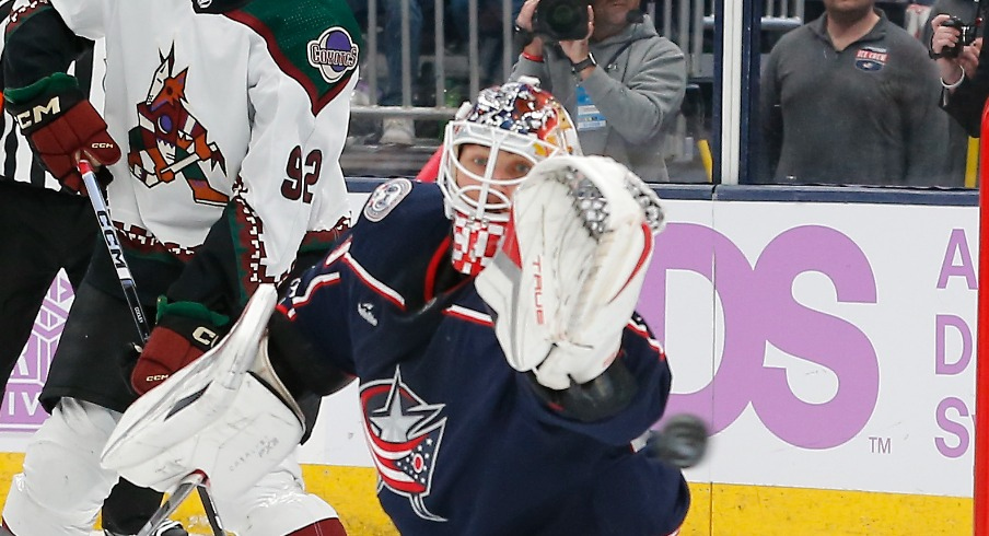 Columbus Blue Jackets goalie Elvis Merzlikins (90) makes a save with Arizona Coyotes center Logan Cooley (92) looking for a rebound during the first period at Nationwide Arena.