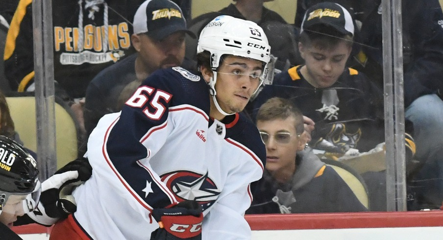 Columbus Blue Jackets center Luca Del Bel Belluz (65) moves the puck away from Pittsburgh Penguins defenseman Ty Smith (24) and forward Jonathan Gruden (45) during the first period at PPG Paints Arena.