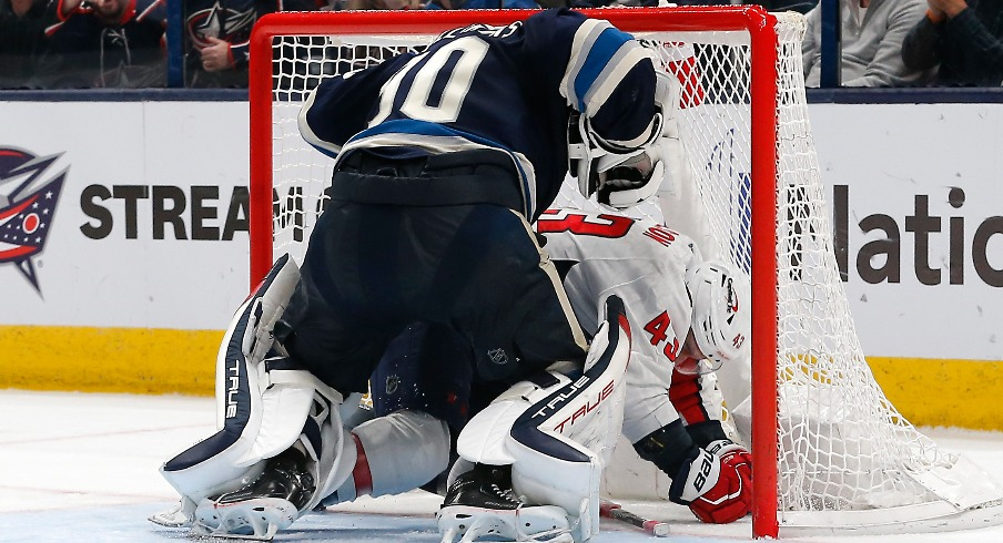Columbus Blue Jackets goalie Elvis Merzlikins (90) and Washington Capitals right wing Tom Wilson (43) tangle inside the net during overtime at Nationwide Arena.