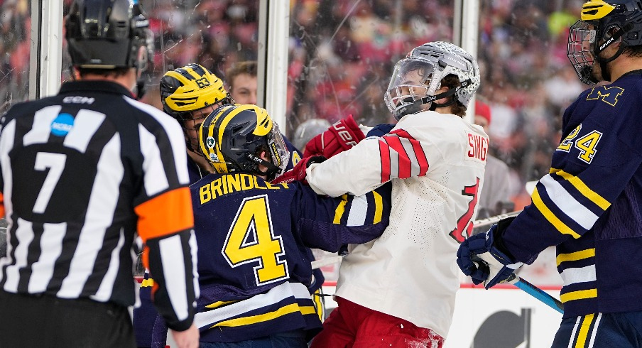 Ohio State Buckeyes forward Tate Singleton (13) hits Michigan Wolverines forward Gavin Brindley (4) during the first period of the Faceoff on the Lake outdoor NCAA men s hockey game at FirstEnergy Stadium.