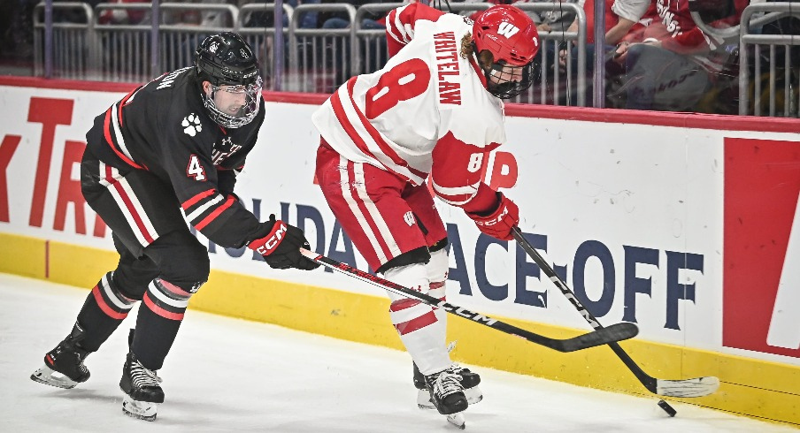 Wisconsin forward William Whitelaw (8) handles the puck behind the net as Northeastern defenseman Pito Walton (4) pursues during the first period of the championship game of the Kwik Trip Holiday Face-Off on Friday, December 29, 2023, at Fiserv Forum in Milwaukee, Wisconsin.