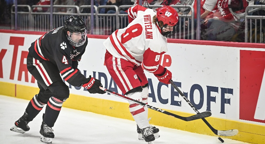 Wisconsin forward William Whitelaw (8) handles the puck behind the net as Northeastern defenseman Pito Walton (4) pursues during the first period of the championship game of the Kwik Trip Holiday Face-Off on Friday, December 29, 2023, at Fiserv Forum in Milwaukee, Wisconsin.