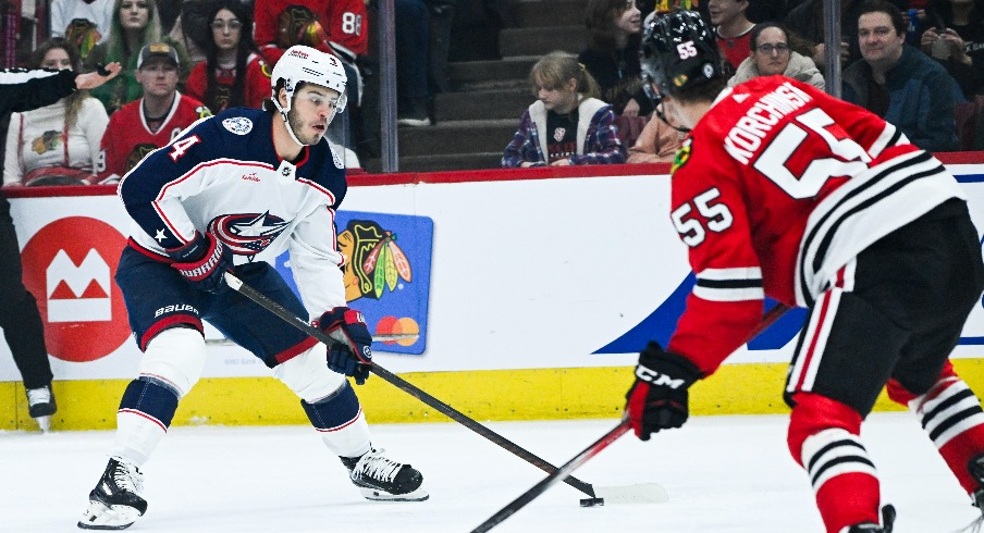 Columbus Blue Jackets center Cole Sillinger (4) moves the puck against Chicago Blackhawks defenseman Kevin Korchinski (55) during the first period at the United Center.