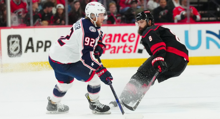 Columbus Blue Jackets' Alexander Nylander holds onto the puck against Carolina Hurricanes' Brent Burns during the first period at PNC Arena.