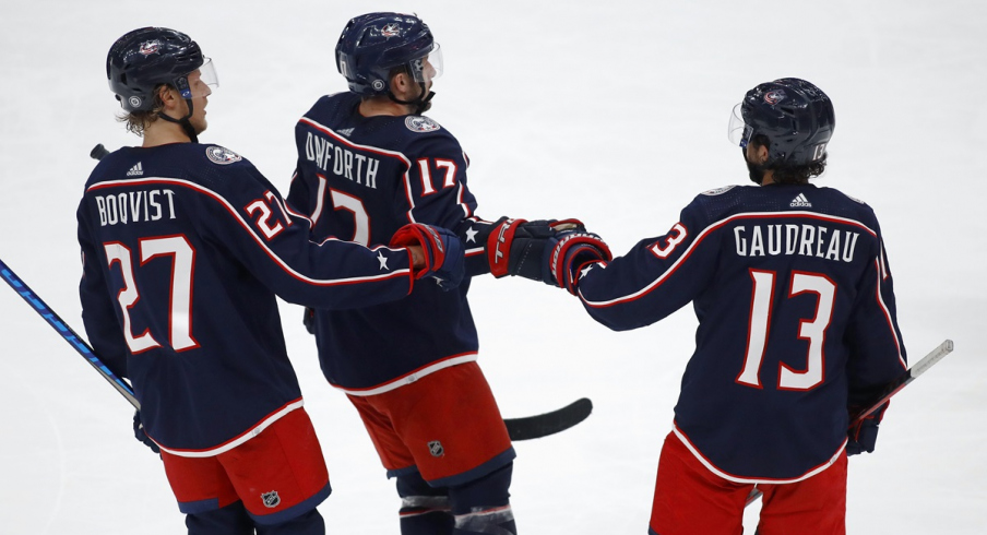 Justin Danforth celebrates with Adam Boqvist and Johnny Gaudreau