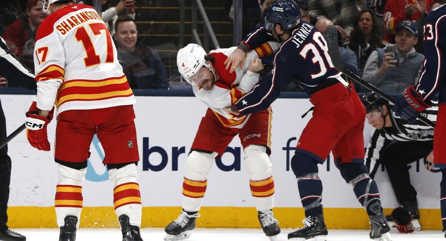 Jan 13, 2026; Columbus, Ohio, USA; Columbus Blue Jackets center Boone Jenner (38) and Calgary Flames defenseman Rasmus Andersson (4) fight during the second period at Nationwide Arena.